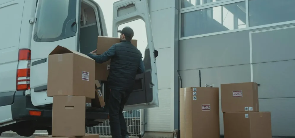 Worker loading moving boxes into a van for transport
