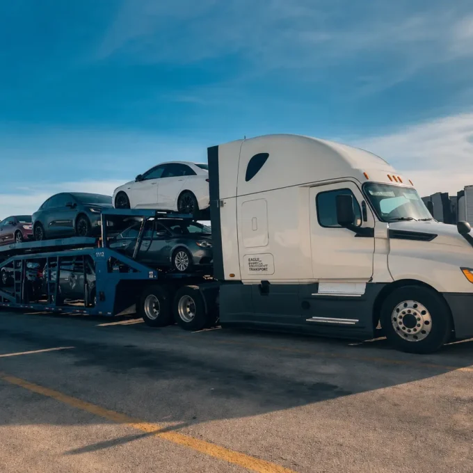 prof_auto_hauling White semi-truck pulling a fully loaded car hauler trailer with secured vehicles ready for safe auto transport
