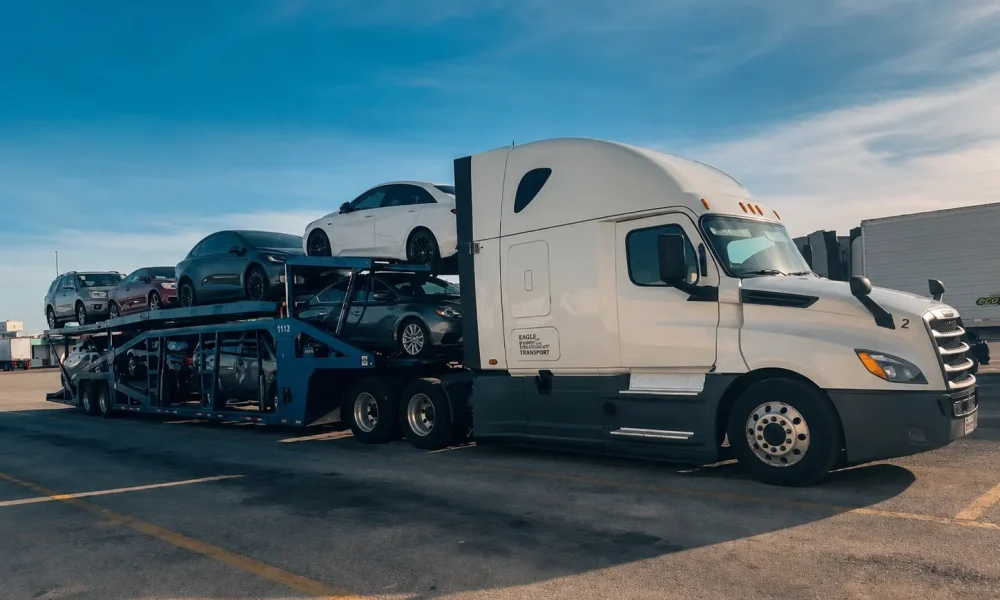 White semi-truck pulling a fully loaded car hauler trailer with secured vehicles ready for safe auto transport